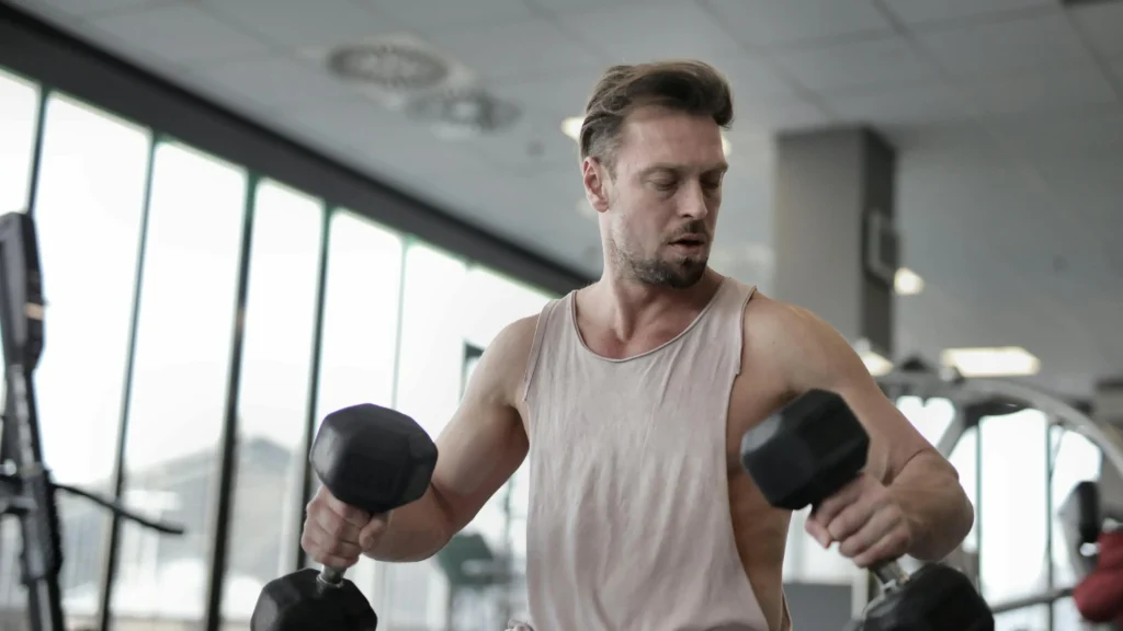 Muscular male with ADHD hyper focus lifting dumbbells on bench in gym