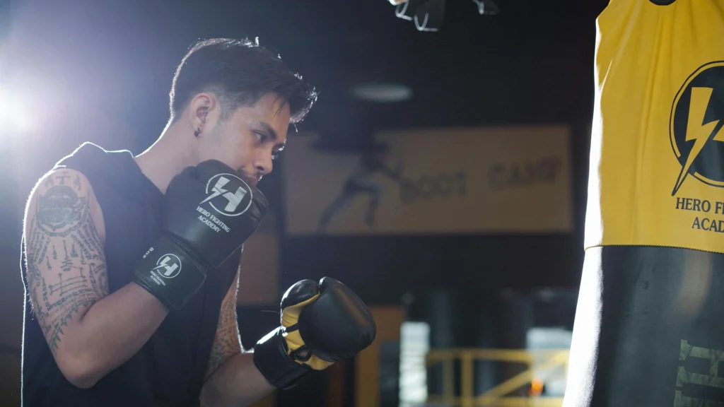 Boxer training with punching bag to improve focus in sports