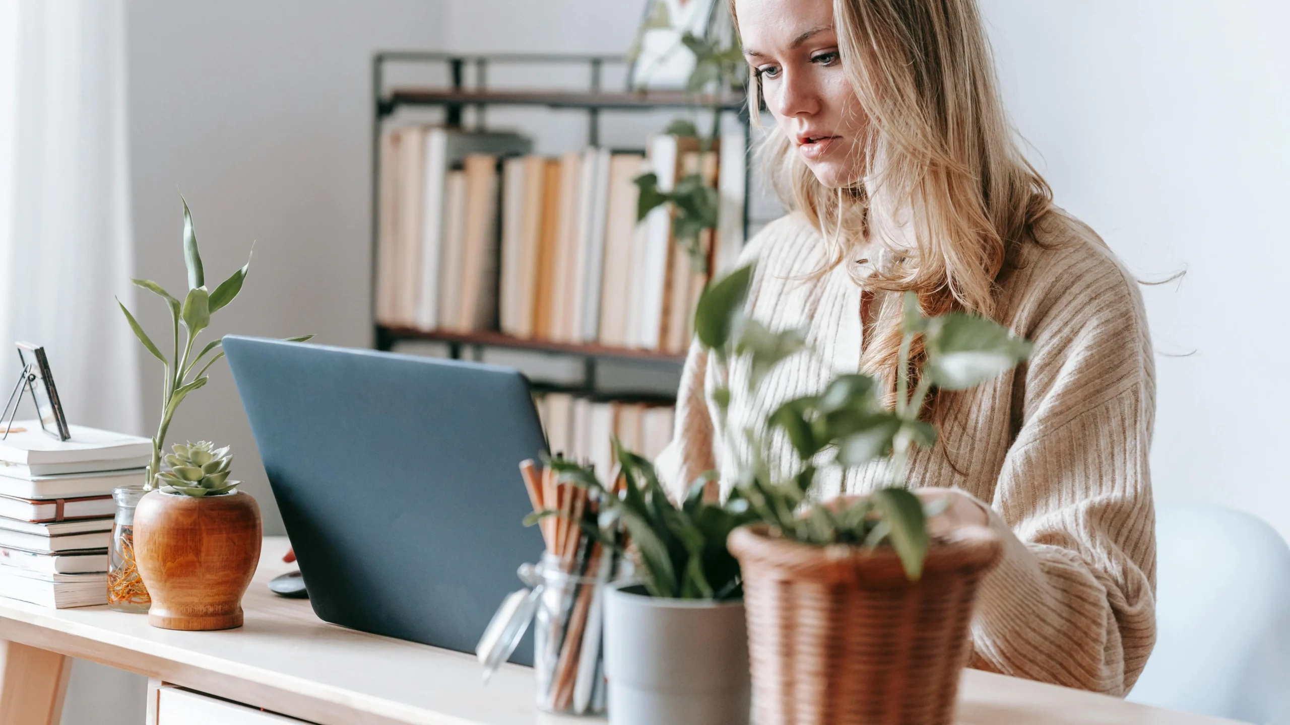 Focused female remote worker using netbook, surrounded by plants, to improve focus naturally.