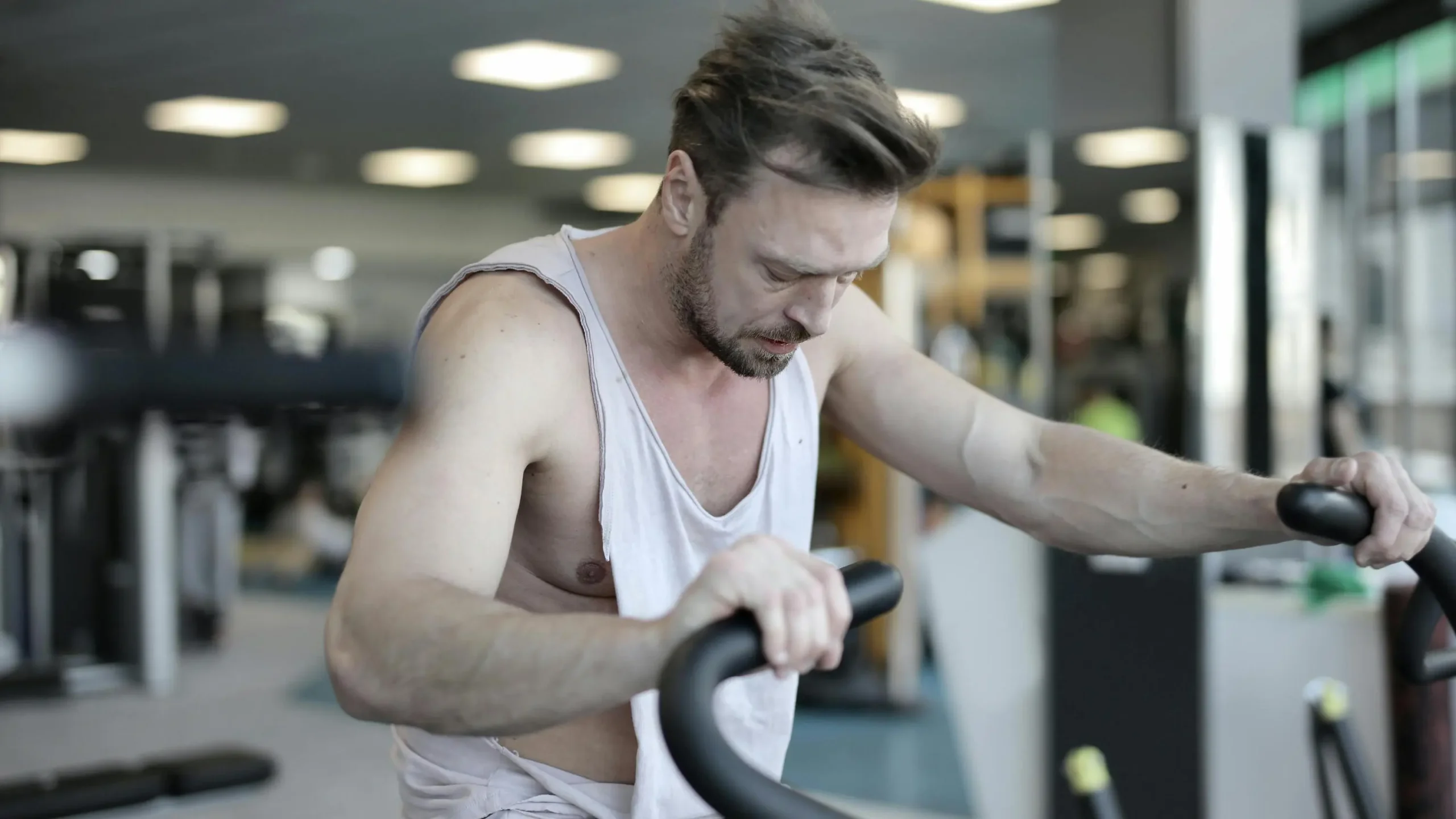 Male athlete training on exercise machine, focusing on metabolic conditioning in sports center