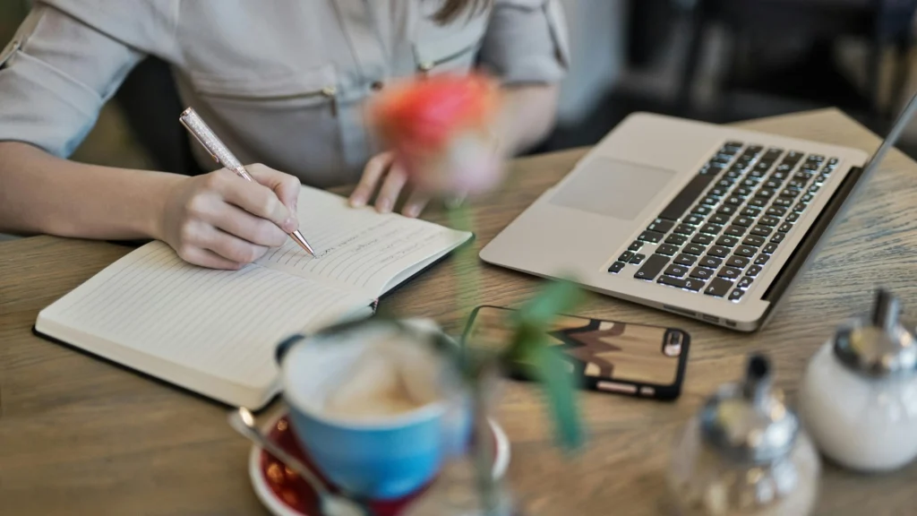 Writing a productivity to-do list beside a MacBook