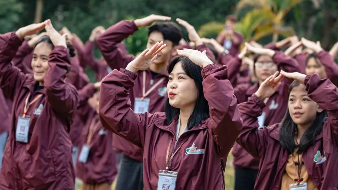 Group of people in maroon jackets doing yoga, best exercise in the morning