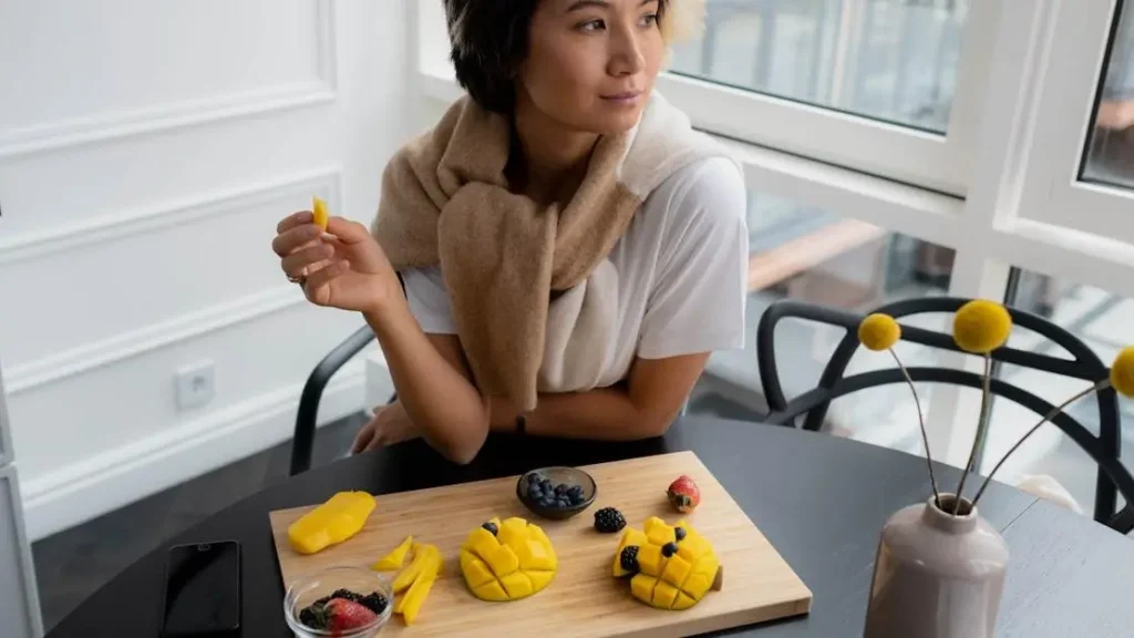 Woman enjoying fruits that improve memory from a wooden chopping board