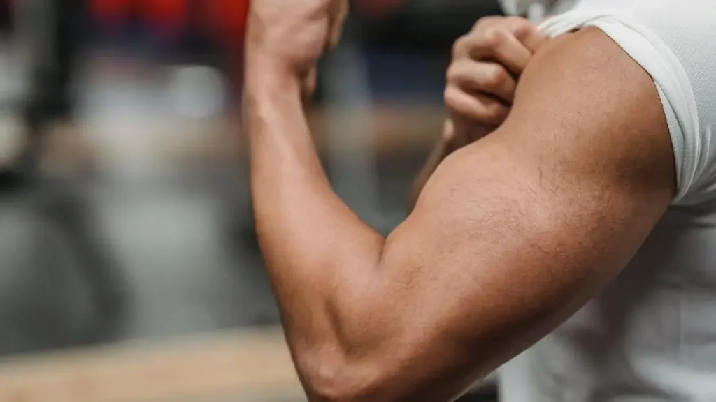 Sportsman in white shirt flexing biceps in gym for article on how much protein for muscle growth