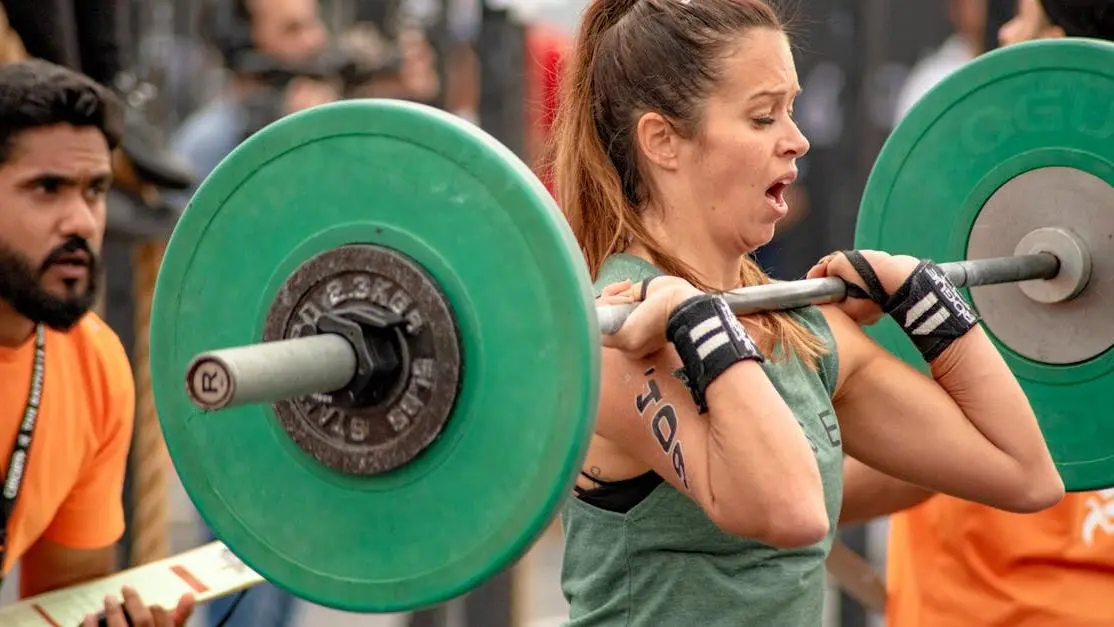 Woman lifting barbell to build muscle through protein intake