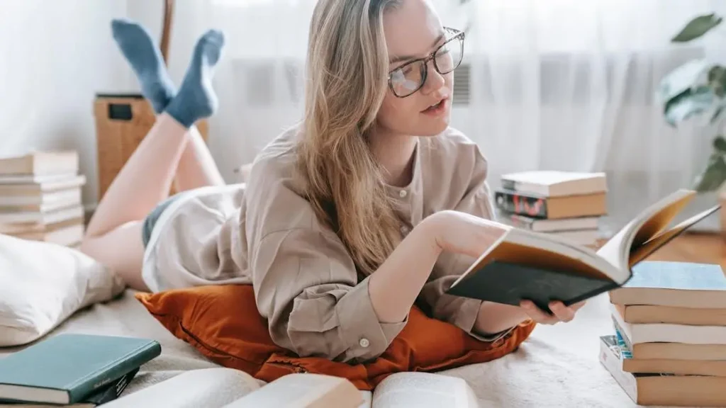 Young woman in eyeglasses reading a book to improve memory for studying at home