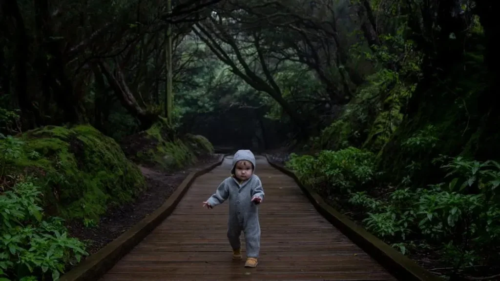 Focused child navigates plank path in dense, dark forest, illustrating short attention span.